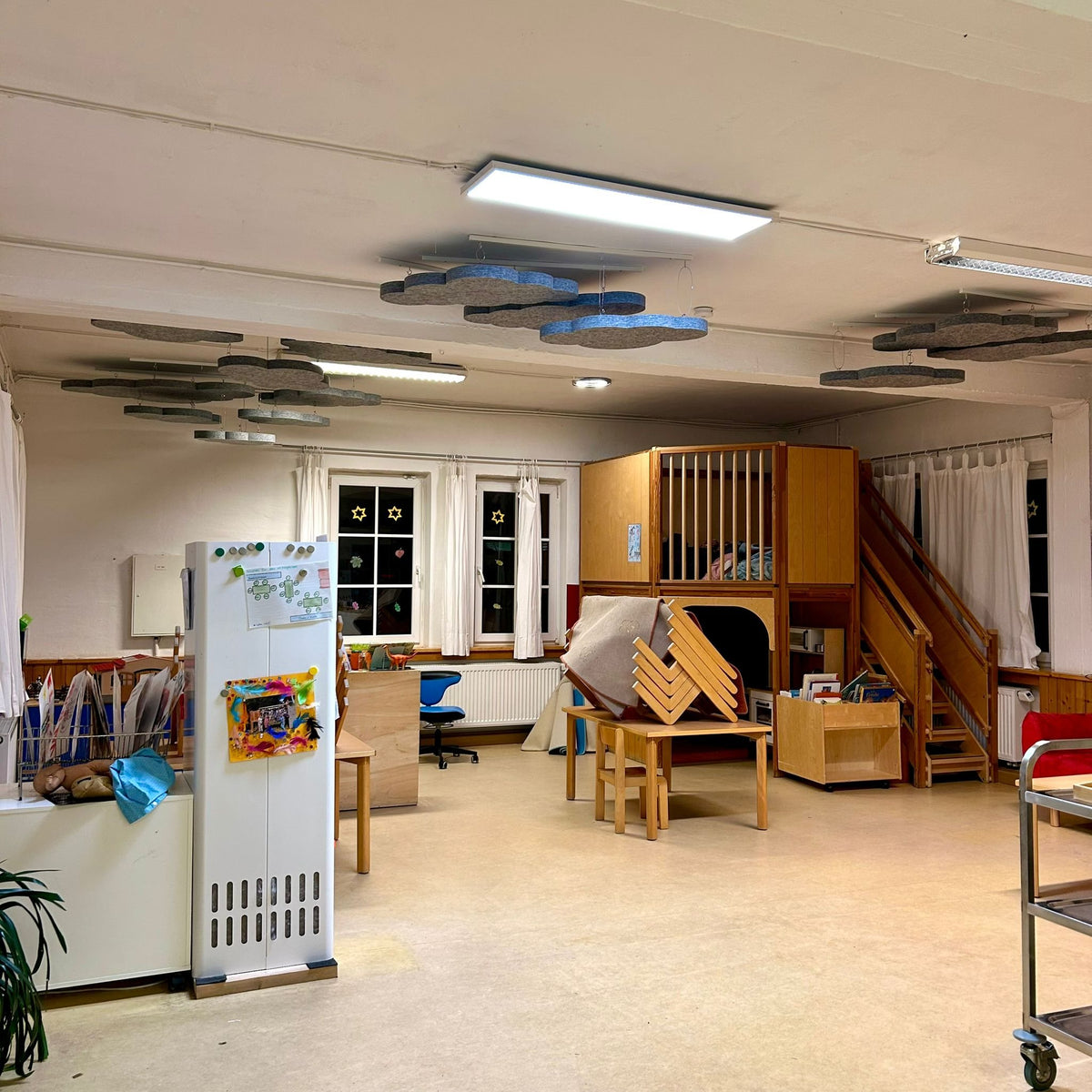 Daycare group room with suspended PET felt cloud absorbers in grey and blue